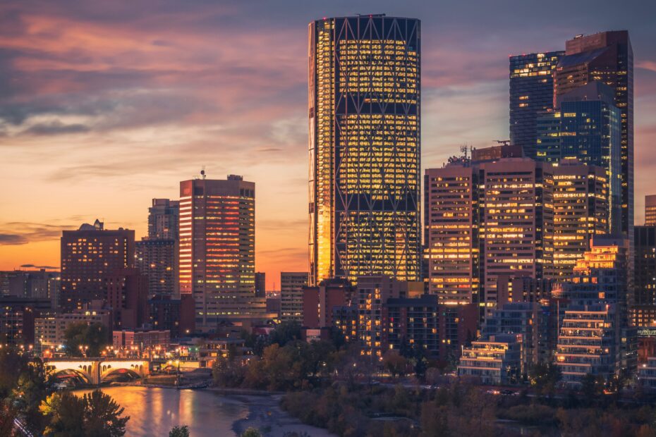 Portrait view of Calgary at dawn, featuring the serene Bow River with the downtown skyline in the background, showcasing the city's beauty and prime real estate.